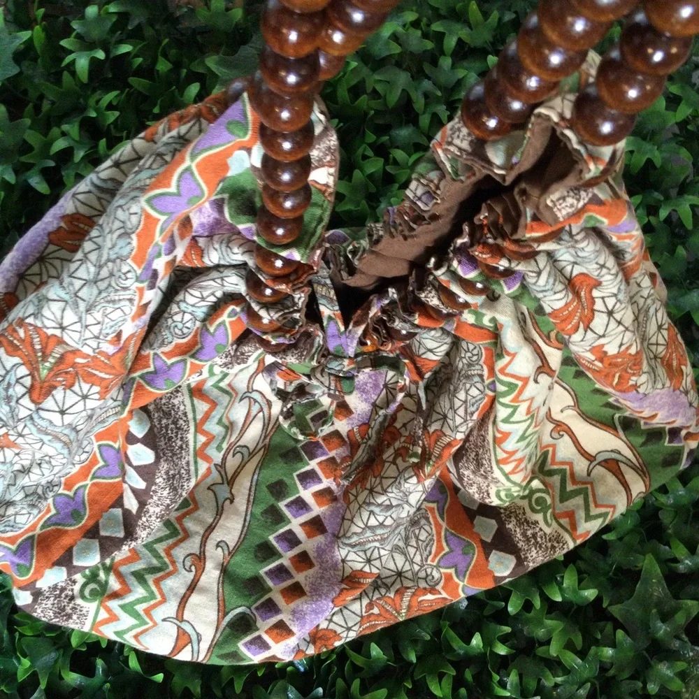Reversible hobo tote with brown wood balls straps. Has a tie strap closu…